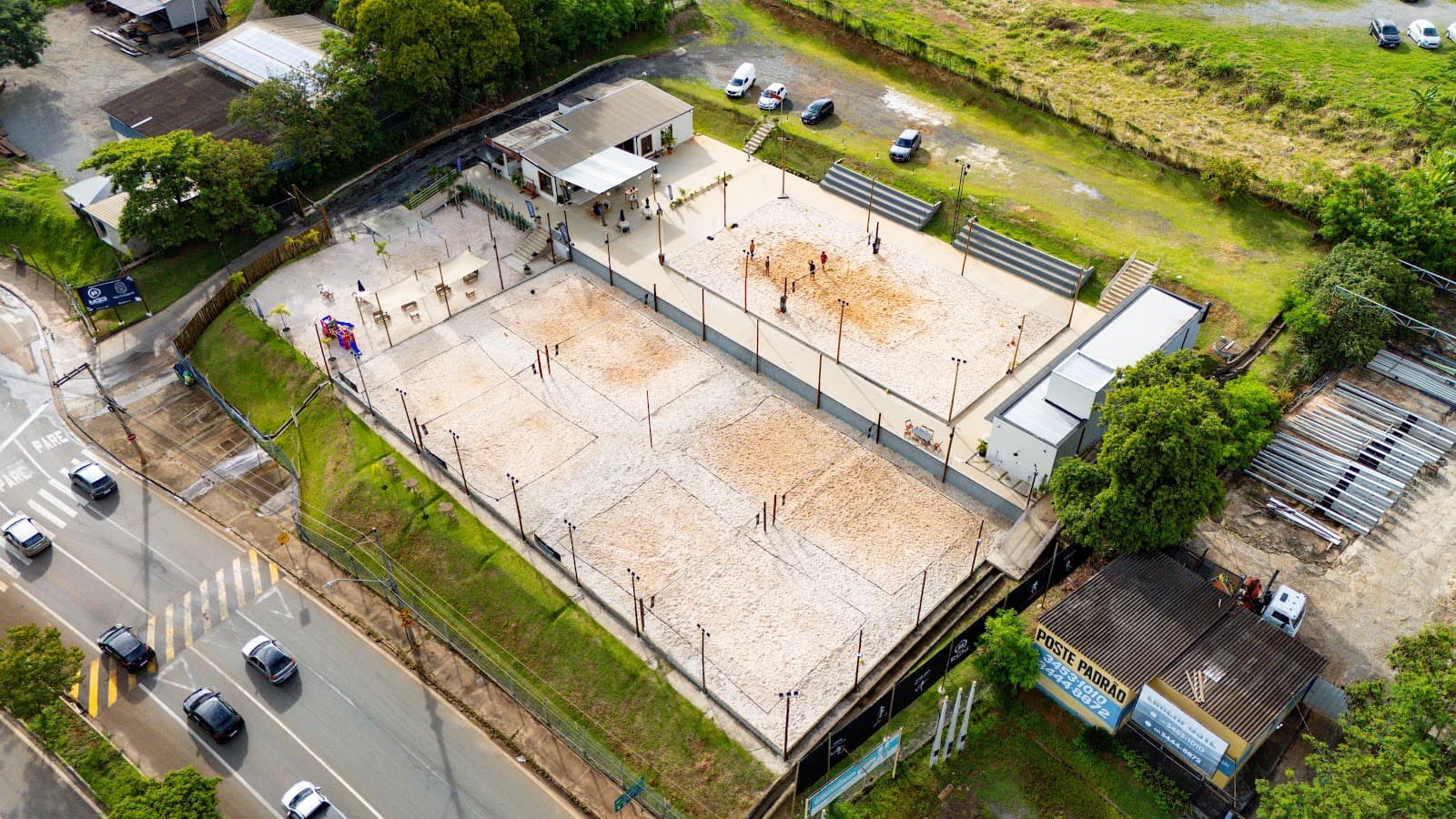 Vista aérea da Arena M33 na beira da avenida, com as quadras de areia, o café e o estacionamento